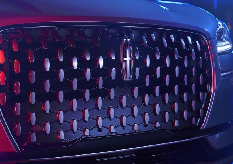 The grille of a 2025 Lincoln Corsair® SUV reflects neon light at night. | Bill Knight Lincoln in Tulsa OK