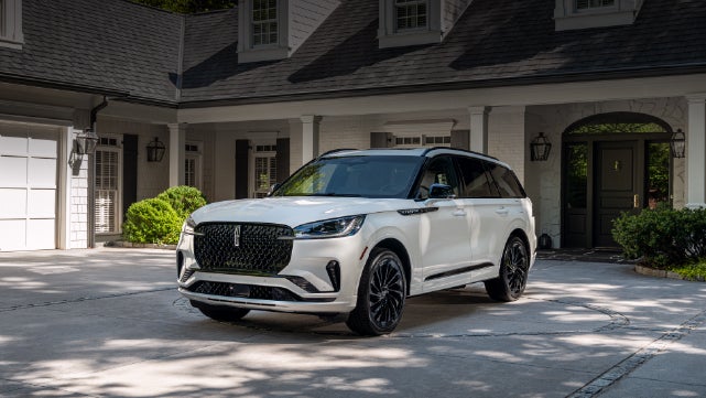 A white 2026 Lincoln Aviator® SUV is parked in the driveway of a luxury home. | Bill Knight Lincoln in Tulsa OK