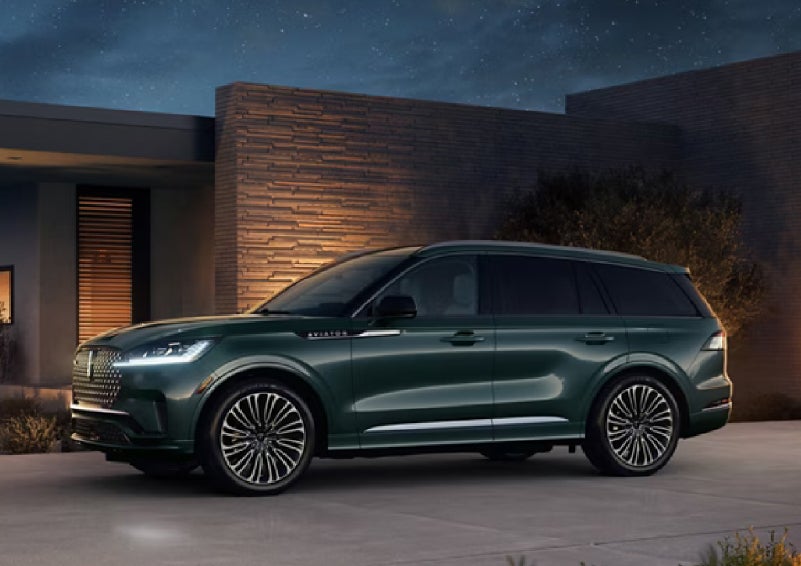 A green 2027 Lincoln Aviator® SUV is parked outside a contemporary home. | Bill Knight Lincoln in Tulsa OK