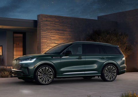 A green 2027 Lincoln Aviator® SUV is parked outside a contemporary home. | Bill Knight Lincoln in Tulsa OK