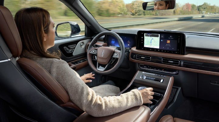 A 2027 Lincoln Aviator® SUV is being driven hands-free on a highway lined with trees. | Bill Knight Lincoln in Tulsa OK