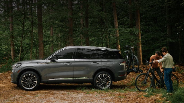 A father and son load e-bikes on a bike rack attached to a 2027 Lincoln Aviator® SUV. | Bill Knight Lincoln in Tulsa OK